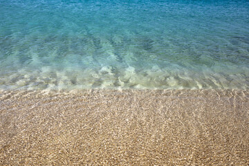 pure turquoise sea water wave spills over the golden sandy shore. natural abstract background in warm tones. sea artistic wallpaper