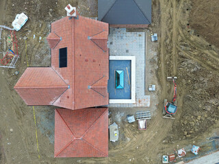 Drone inspection view of a large, near completed family home seen with a newly fitted glass lantern on the conservatory roof. Seen at a British housing development site.