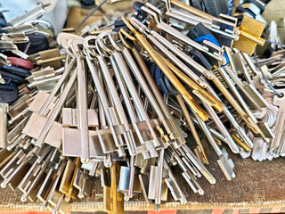 Collection of various metal keys arranged in a messy pile at a street market during the afternoon...