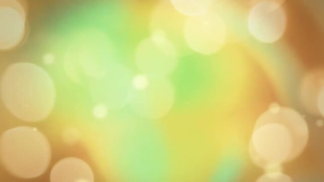 Soft and shimmering golden yellow and lime green bokeh light background loop with flying subtle dust particles