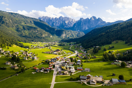 Aerial view of verdant meadows meet quaint villages nestled beneath the towering, jagged peaks of the Austrian Alps, Gosau, Upper Austria, Austria.
