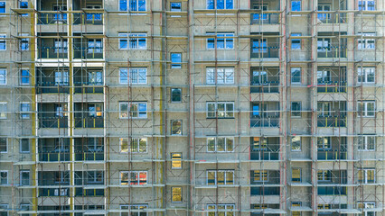 Facade of residential building under renovation with scaffolding and windows, modern architecture and construction progress