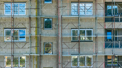 Close view of apartment building facade with scaffolding during renovation, construction and modernization work in city
