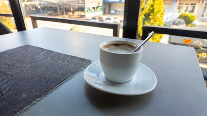 Cup of coffee with spoon on modern cafe table, morning light and relaxing lifestyle atmosphere