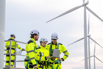 Engineer team in safety harnesses, collaborating on maintenance platform for wind turbine inspection. On-site service team with PPE, planning and inspecting wind turbines from a maintenance lift.