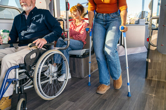 African woman with crutches and senior man in wheelchair riding public transport. Promoting accessibility and inclusion for all