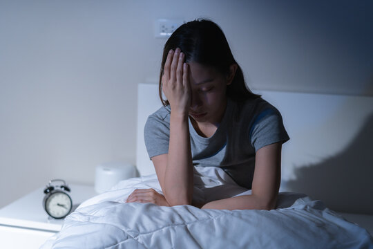 Sad worried and stressed, depressed asian young woman, girl suffering in bed from insomnia problem, awake at night, hand covering face from trouble disturbed loud noise, unable sleep. Restless people.