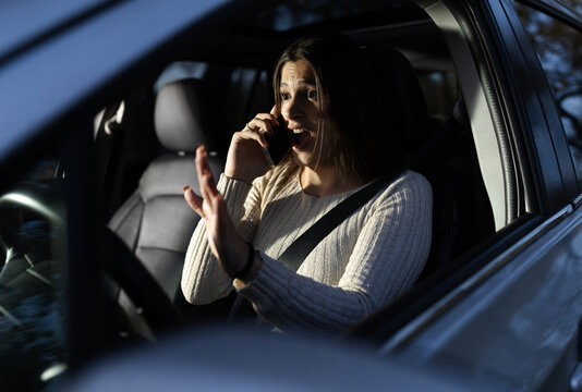 Woman driving car and seems shocked while having call on phone - Powered by Adobe