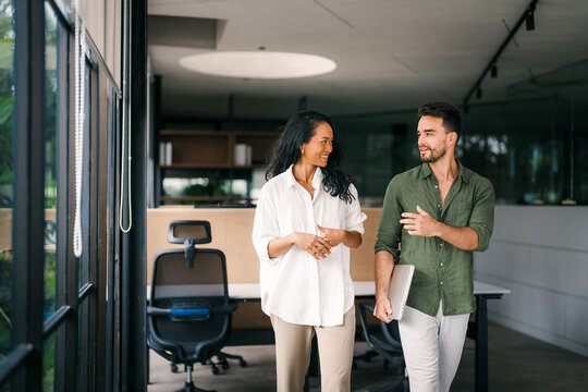 Diverse colleagues woman and man together, discussing online project and having fun in office