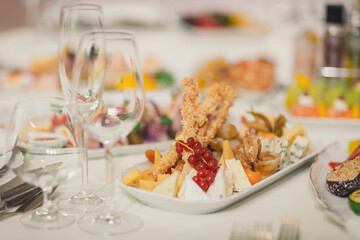 Deluxe platter of assorted cheeses, fruits, and crispy snacks prepared for a festive occasion in an elegant dining setting at night