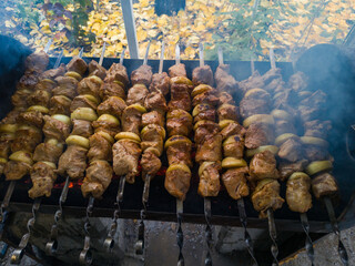 Shish kebab on the grill in autumn. Meat on the fire. A man skewers marinated pork on metal barbecue skewers over a fire, close-up. Preparing food outdoors.