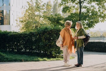 Fototapeta premium Two senior women talking and smiling in a city park