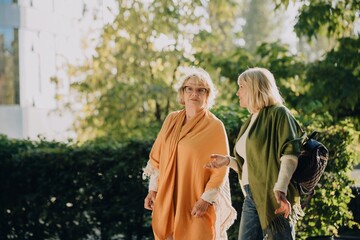 Two senior women talking while walking in a park
