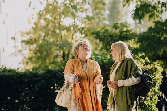 Two senior women talking and walking in a park