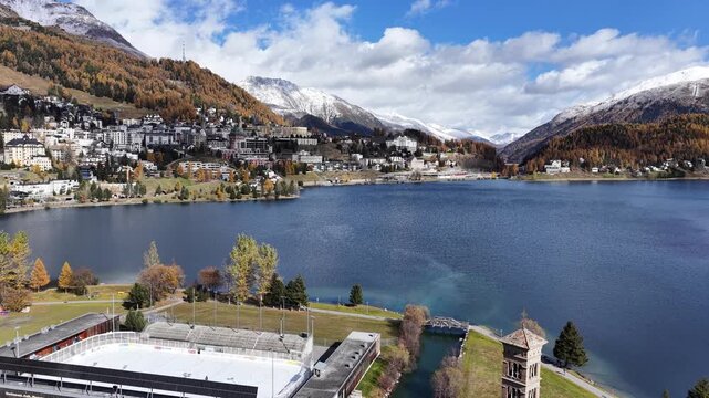 St. Moritz lake in Engadin Graub&uuml;nden Switzerland with clear water, autumn trees and snowy mountains from drone push forward.