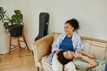 Happy african american lesbian couple enjoying cozy time in their modern apartment