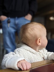 A one-year-old toddler focused on taking his very first independent steps on the floor.

