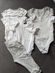 A minimalist flat lay of essential newborn baby clothing items on a neutral background.

