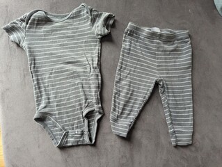 Tiny newborn baby clothes neatly arranged on a soft blanket. Essential wardrobe for the first days.

