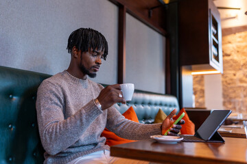 Young black man drinking coffee checking smartphone