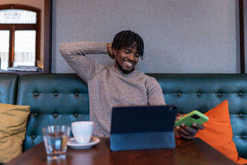 Happy man relaxing smiling using digital devices in cafe