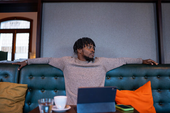 Young man relaxing in lobby, looking away while using tablet