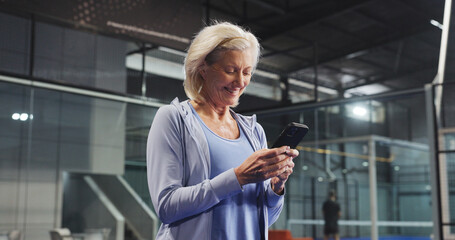 Sport, senior woman and phone on court for padel match score, track performance and game break. Retirement fitness, elderly person and smartphone at indoor tennis club for practice schedule and chat
