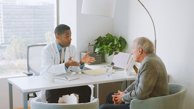 Senior Man In Hospital Office Having Consultation With Male Doctor