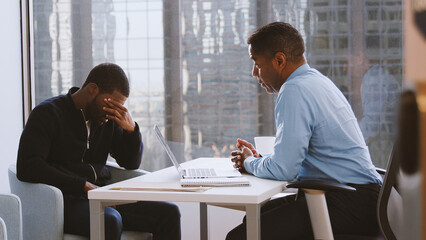 Worried Man Having Consultation With Male Doctor In Hospital Office