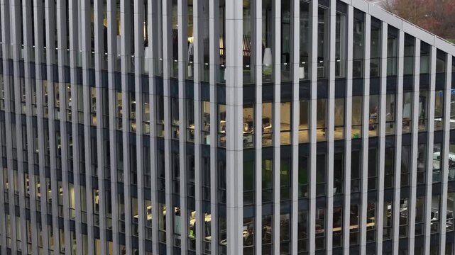 Aerial view of a contemporary office building in Vilnius, Lithuania, with a geometric rooftop design, glass facade, and visible workspaces through large vertical windows.