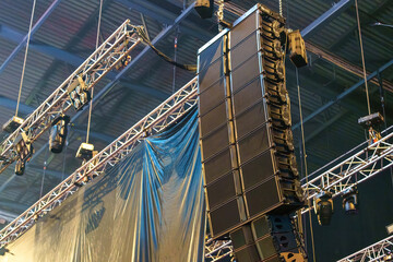 Industrial speakers rigged and suspended in a venue, ready to deliver powerful sound for the upcoming event
