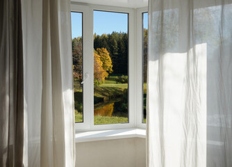  View from the window  on yellow treesin a garden, landscape with autumn forest, window frame.