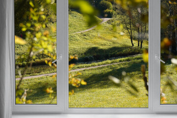  View from the window  on yellow treesin a garden, landscape with autumn forest, window frame.