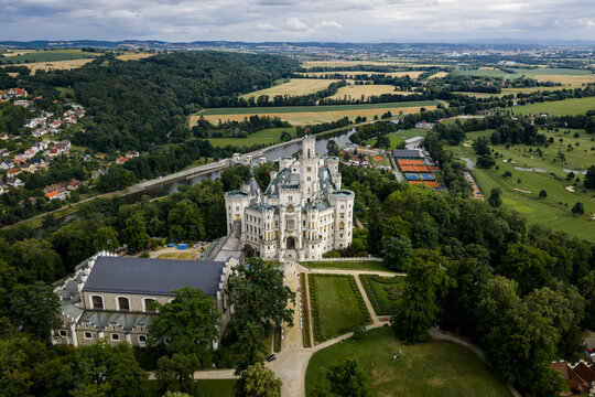 Aerial view of the stunning white Hlubok&aacute; Castle with its ornate spires, surrounded by lush green forests and the winding Vltava River, Hluboka nad Vltavou, Jihocesky kraj, Czechia.