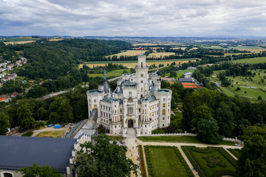 Aerial view of the striking white Hlubok&aacute; Castle stands majestically amidst lush green trees and manicured gardens, a beacon of history, Hluboka nad Vltavou, Jihocesky kraj, Czechia.