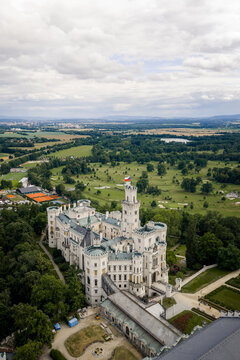 Aerial view of the pristine white Zamek castle, a beacon of architectural elegance amidst verdant forests and manicured lawns, Hluboka nad Vltavou, Jihocesky kraj, Czechia.
