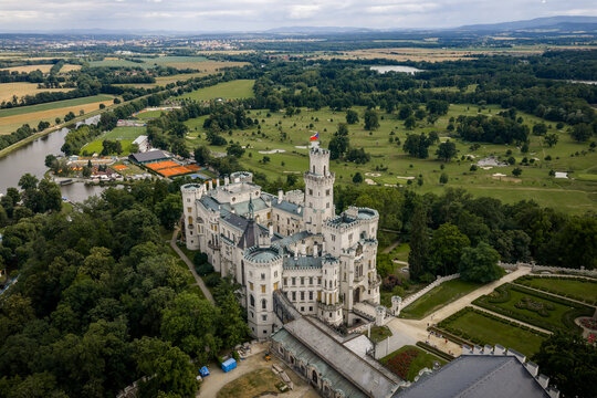 Aerial view of the imposing Zamek Hluboka Castle, its white facade contrasting against the verdant trees and distant fields, Hluboka nad Vltavou, Jihocesky kraj, Czechia.