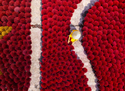 Aerial view of vibrant red incense sticks drying under the sun, creating a mesmerizing pattern of color and texture, Quang Phu Cau, Hanoi, Vietnam.