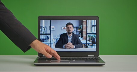 A professional live streaming studio setting with a laptop in front of a green screen, showing a man in a virtual meeting.
