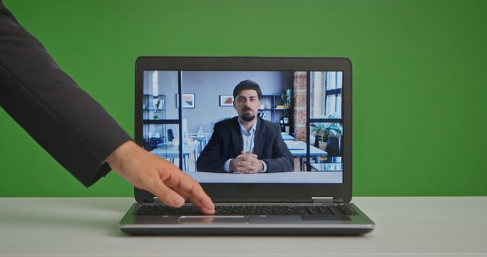 A professional live streaming studio setting with a laptop in front of a green screen, showing a man in a virtual meeting.