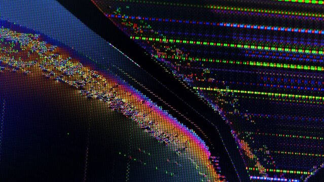Close up of a broken TV screen displaying colorful pixel distortion and crack lines from impact.
