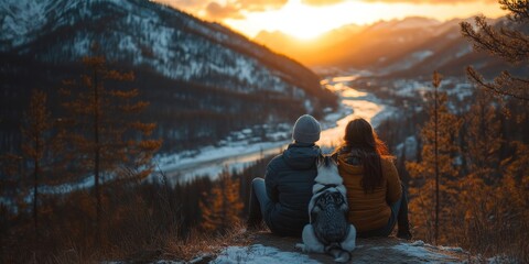 Couple and dog sitting mountain sunset winter.