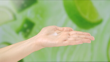 Close up of a hand with lotion against a blurred green citrus background, symbolizing freshness and skincare. Concept of beauty, skin care, and cream presentation.
