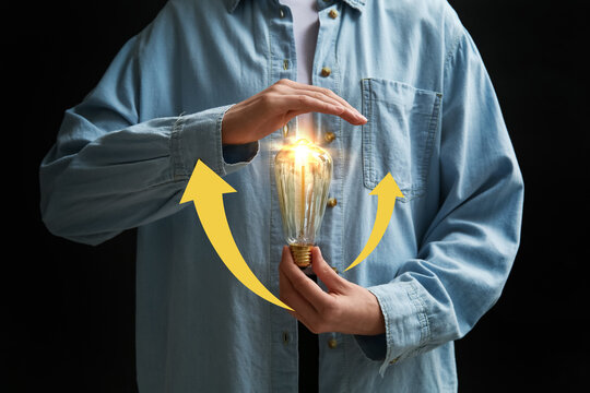 Woman holding retro light bulb on black background. Closeup - Powered by Adobe