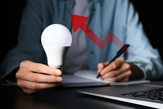 Woman with light bulb doing notes on black background. Closeup