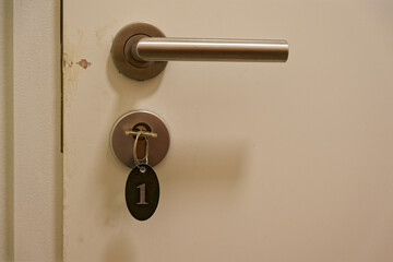Obraz premium Metal door handle and key with number 1 tag hanging in modern apartment interior