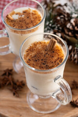Eggnog with Cinnamon and Christmas Decorations on wooden table