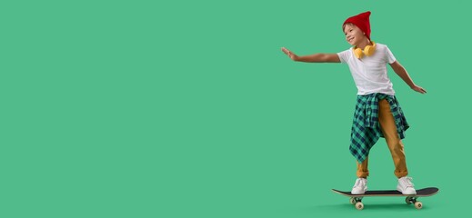 Little boy riding skateboard on green background with space for text