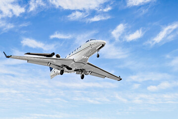 Private business plane flying under blue sky with white clouds	