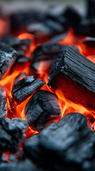 Close-up of hot glowing coals with orange light and dark texture.  
